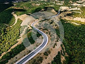 Aerial above view of a rural landscape with a curvy road running through it in Greece.