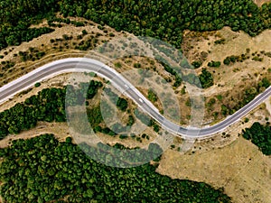 Aerial above view of a rural landscape with a curvy road running through it in Greece.