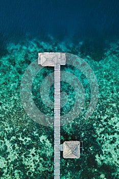 Aerial abstract view of wooden boat pier on tropical island with coral reef