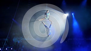 Aerial acrobat on the circus stage. A young girl and a guy perform acrobatic elements on the air ring, in the circus