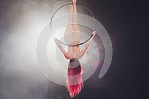 Aerial acrobat in the ring. A young girl performs the acrobatic elements in the air ring.