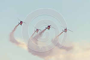 Aerial aerobatics with helicopters flying in the sky leaving a smoke trail photo