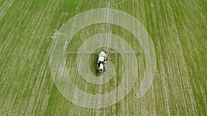 Aerial agricultural machinery works on farm, tractor sow wheat crops moves across the field and sprays fertilizer