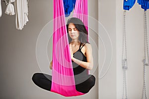 Aerial antigravity yoga girl in lotus pose on silk hammock