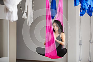 Aerial antigravity yoga girl in lotus pose on silk hammock