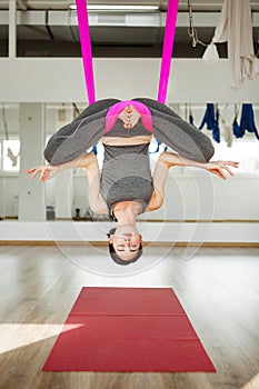 Aerial antigravity yoga. Girl in upside down lotus pose