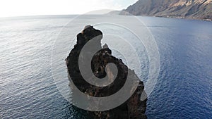 Aerial arc shot around rock Roque de La Bonanza at sunrise sun, Hierro