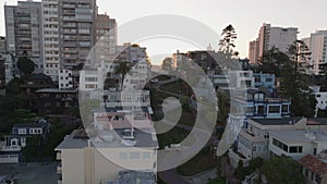 Aerial ascending footage of famous tourist attraction, Lombard Street with turns. Buildings in city at sunset.