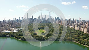 AERIAL: Beautiful Central Park view with lake and Manhattan Skyline in Background at sunny summer day, New York City