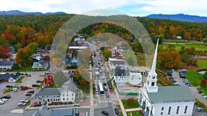 Aerial through beautiful small Vermont town of Stowe in peak fall foliage with focus on church
