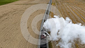 Aerial from behind Steam Train Billowing Smoke Across Farm Fields
