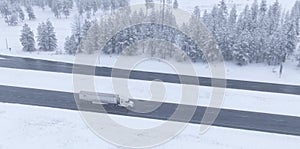 AERIAL: Big commercial truck hauls a heavy container along dangerous icy highway