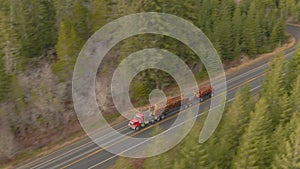 AERIAL: Big rig speeds down the rural freeway with a trailer full of logs.
