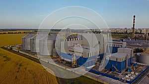 Aerial of big steel grain silos elevators storage at the yellow wheat field. Agriculture industry 4k aerial video of