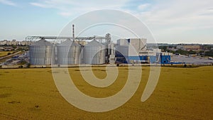 Aerial of big steel grain silos elevators storage at the yellow wheat field. Agriculture industry 4k aerial video of