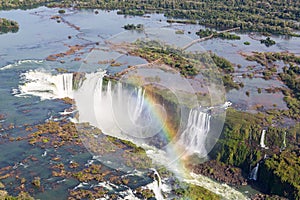 Aerial bird`s-eye view of beautiful rainbow above Iguazu Falls Devil`s Throat chasm from a helicopter flight. Brazil and Argentina