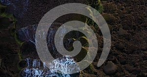 Aerial bird`s eye view panning over limestone outcrop being washed ocean waves