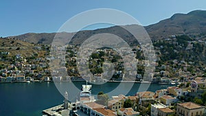 Aerial bird`s eye view video taken by drone of beautiful picturesque houses with views to port of Symi island