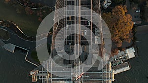 Aerial birds eye overhead top down panning view of vehicles driving on Brooklyn bridge over river. Heavy traffic on road