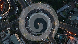Aerial birds eye overhead top down rotating view of busy city traffic in the Selamat Datang Monument roundabout at night