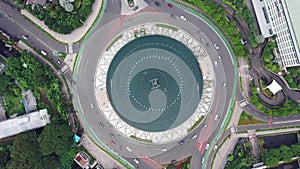 Aerial Birds Eye Overhead Top Down rotating View of busy city traffic in the Selamat Datang Monument roundabout at night