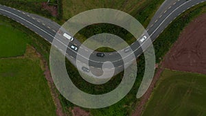 Aerial birds eye overhead top down view of cars passing turns on road in countryside. Ireland