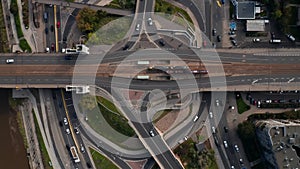 Aerial birds eye overhead top down view of traffic on road intersection on riverbank. Trams stopping at tram stop