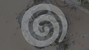 Aerial: birds view down on Venice Beach Skatepark with Visitors,Skaters and Palmtrees, Sunset Skating in Los Angeles