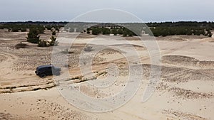 AERIAL. Black SUV rides on a sandy road.