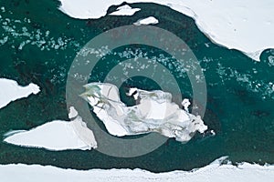 Aerial of a blue and green river with snow and crushed ice during an ice drift in winter in the Altai mountains in Russia