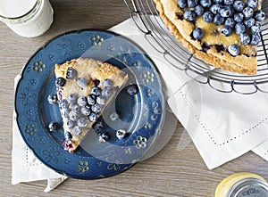 Aerial of blueberry tart on blue plate, on tabletop with napkin.