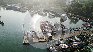 Aerial bustling harbor with vibrant fishing vessels. Fishermen prep boats for sea voyage. Morning sun on ocean surface
