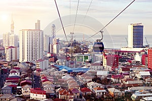 Aerial cableway above city roofs of Batumi, Georgia. Urban landscape with high-rise and ordinary single storey houses and sea.