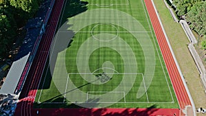 Aerial camera view on the forest and the stadium. View of the football field and athletics stadium. View of the city and downtown