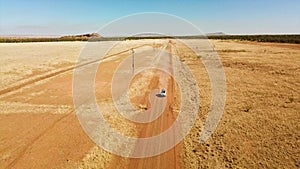 Aerial, car driving on dusty dirt road in remote dry arid Australia