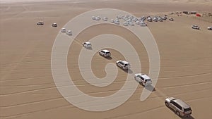 AERIAL: cars driving through desert. Stock. Aerial view of 4x4 off road land vehicle taking tourists on desert dune