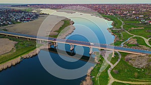 Aerial cinematic drone footage of bridge over river in country area with moving cars and reflection in deep blue water