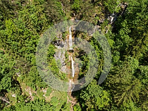 AERIAL: Cinematic view of a gorgeous cascading waterfall in green Logar Valley.