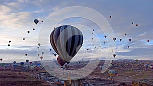 Aerial cinematic view of hot air balloons movements over fairy chimneys covered with snow in Cappadocia, Turkey