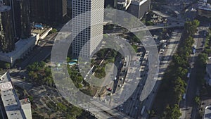 AERIAL: Circiling Downtown Los Angeles, California intersection traffic with palm trees and Skyline in background at