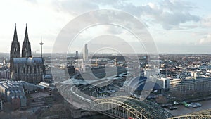 AERIAL: Circling around Beautiful Cologne Cathedral with Central Train Station in beautiful hazy Sunlight