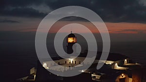 Aerial circling around sensational lighthouse in Lagos Algarve, Portugal, light flashing at dusk