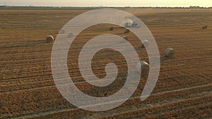 Aerial circling view of tractor tow trailed bale machine to collect straw from harvested field