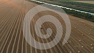 Aerial circling view of tractor tow trailed bale machine to collect straw from harvested field aerial circling view of tractor tow