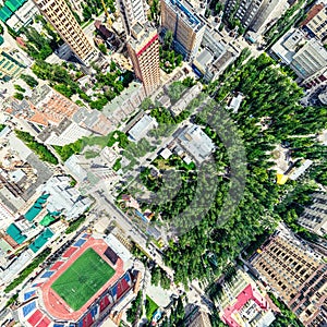 Aerial city view with crossroads and roads, houses, buildings, parks and parking lots. Sunny summer panoramic image