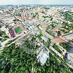 Aerial city view with crossroads and roads, houses, buildings, parks and parking lots. Sunny summer panoramic image