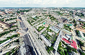 Aerial city view with crossroads and roads, houses, buildings, parks and parking lots. Sunny summer panoramic image