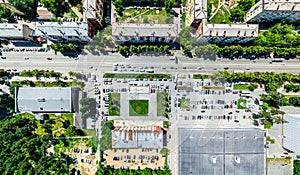 Aerial city view with crossroads and roads, houses, buildings, parks and parking lots. Sunny summer panoramic image