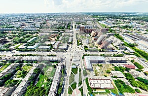 Aerial city view with crossroads and roads, houses, buildings, parks and parking lots. Sunny summer panoramic image