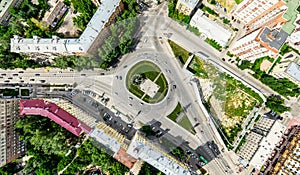 Aerial city view with crossroads and roads, houses, buildings, parks and parking lots. Sunny summer panoramic image